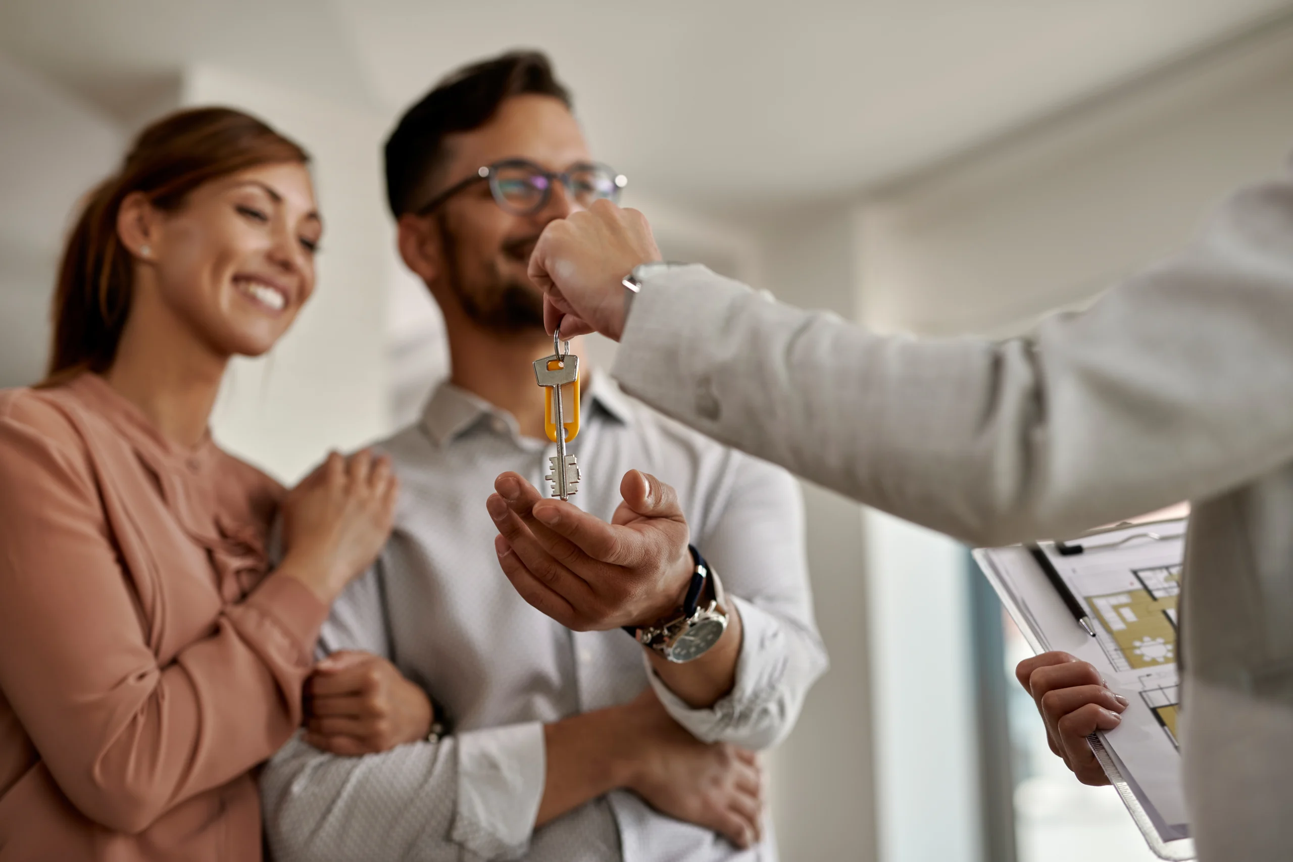 Corretor imobiliário entregando a chave da casa nova para o casal. O concurso CRECI MG abriu vagas para 14 candidatos.