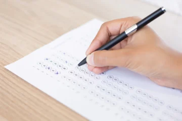 Mão preenchendo a prova do concurso Prefeitura de Bebedouro.