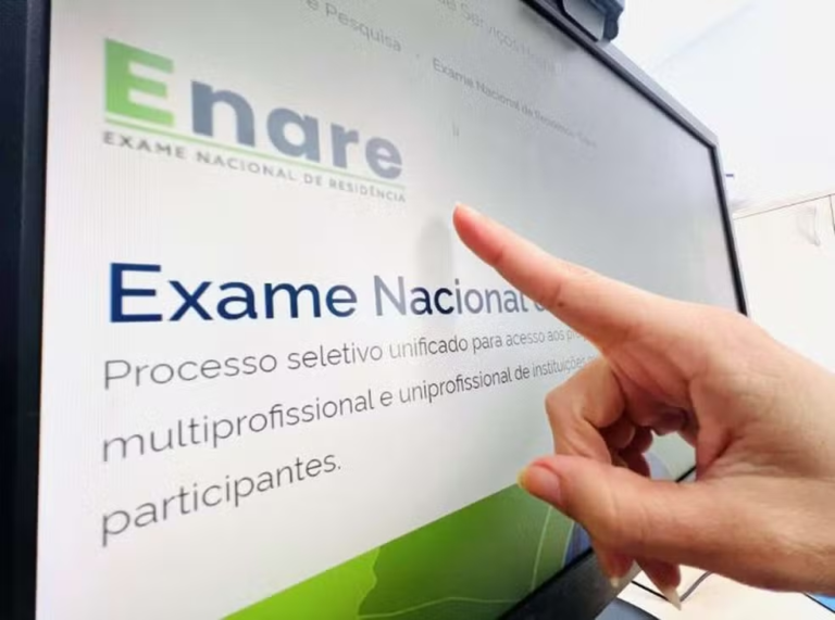 Dedo apontando para tela do computador, onde está a notícia do Enare 2025