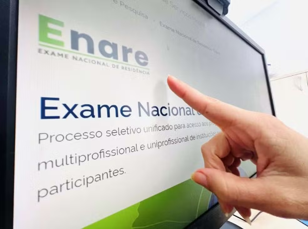 Dedo apontando para tela do computador, onde está a notícia do Enare 2025