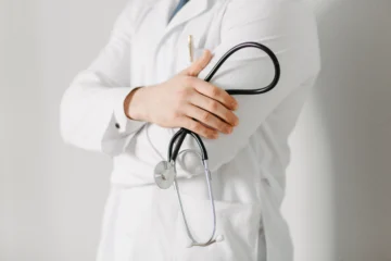 Médico com jaleco branco segurando um estetoscópio. Candidatos do concurso CRM ES estão participando para serem médicos.
