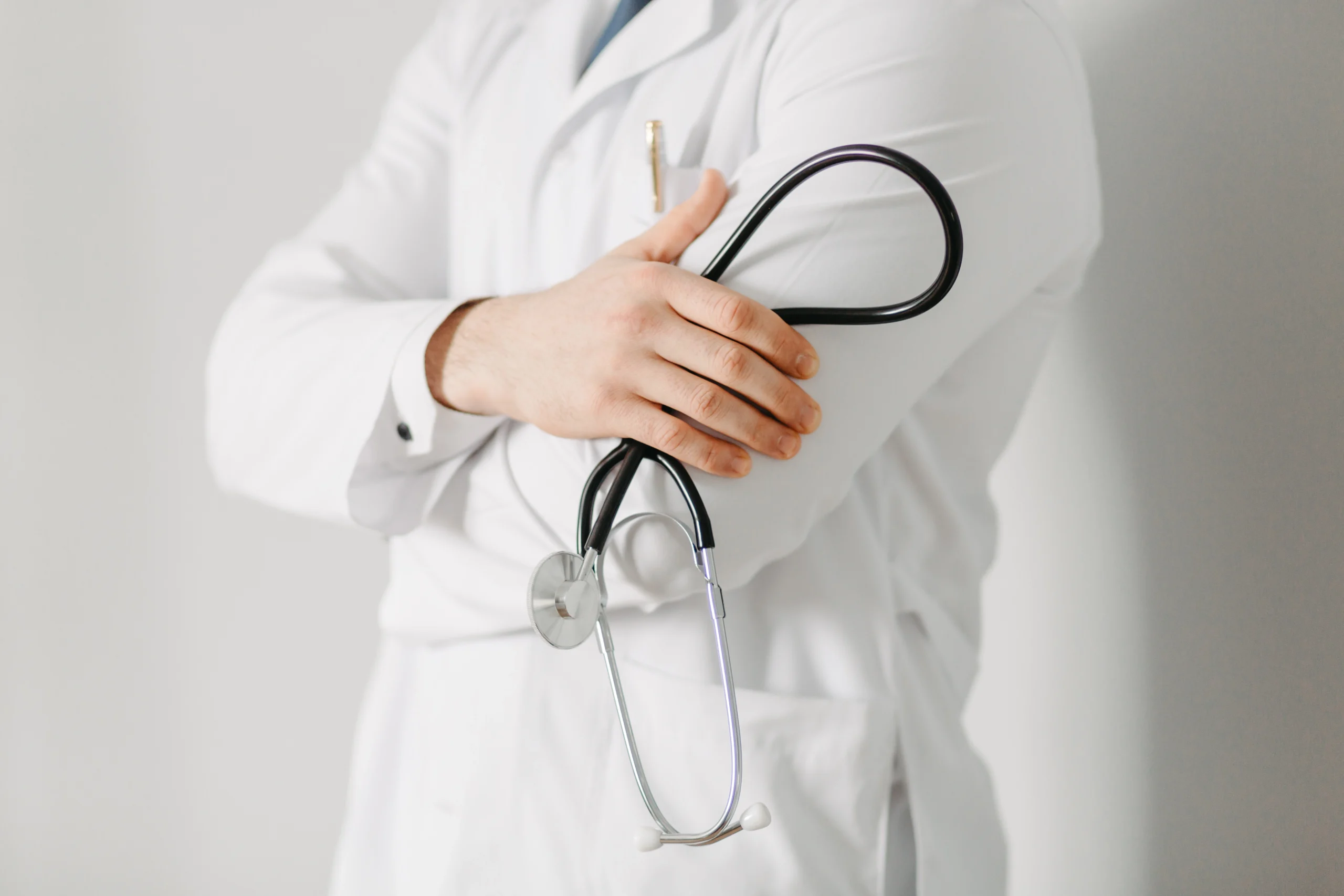 Médico com jaleco branco segurando um estetoscópio. Candidatos do concurso CRM ES estão participando para serem médicos.