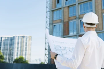 Arquiteto segurando planta do edifício. Vagas abertas do concurso CAU MA para engenheiros.