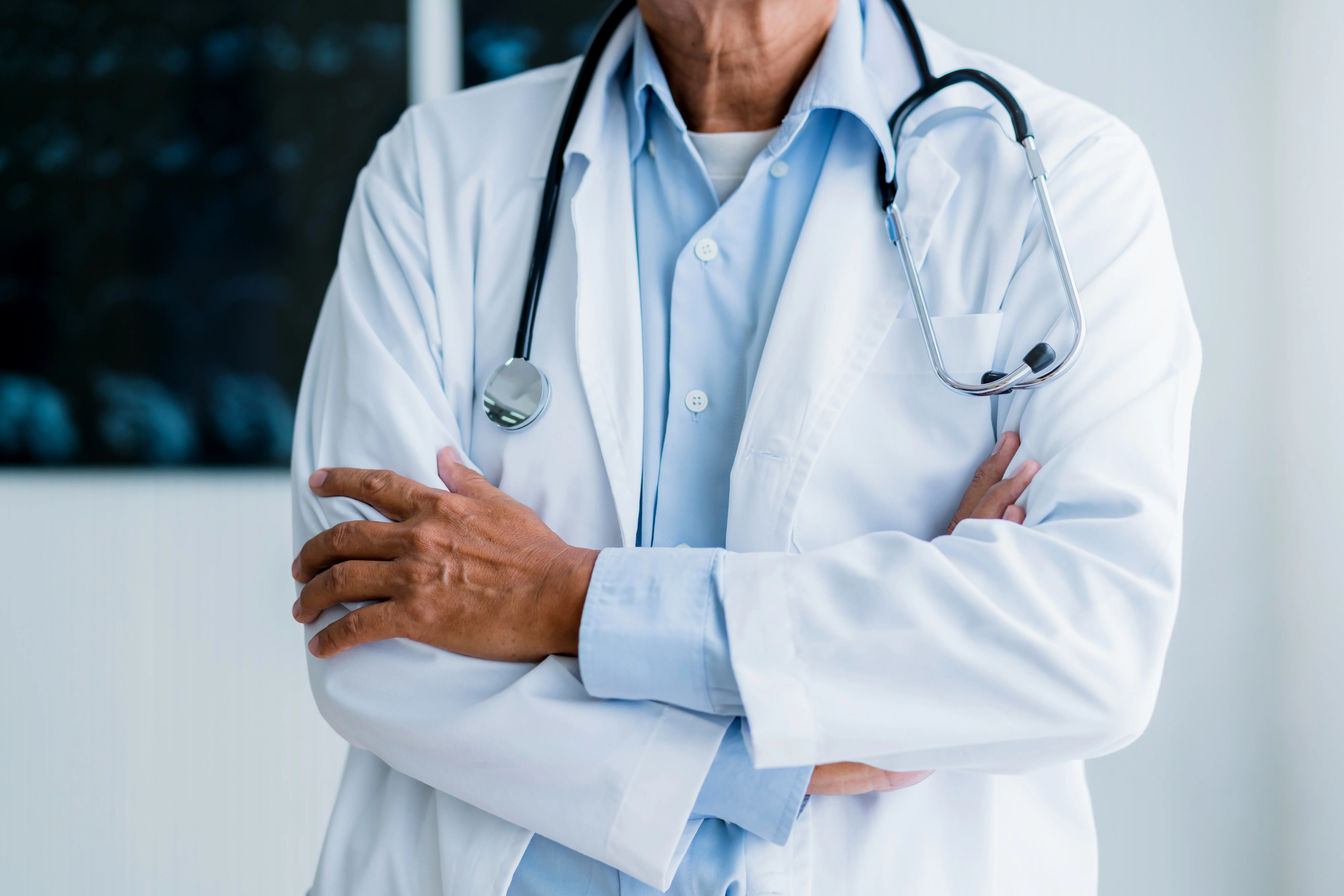 Médico em pé com os braços cruzados
